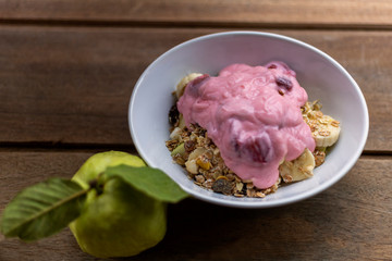 Healthy food yogurt strawberry, banana, guava, and oat in white bowl on wood table.