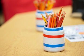 Plastic cup with pencils on a wooden table