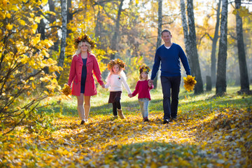 Mom dad children walk in the autumn park. Family for a walk in the forest
