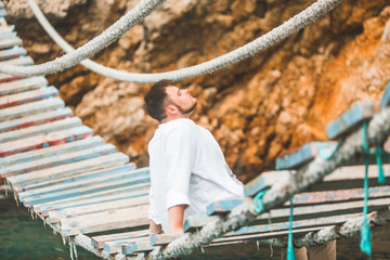 man sitting at suspension bridge enjoying sea view and nature calmness