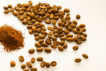 Ground coffee and beans on a white background. Coffee grounds and fried beans on a white table, close up. International Coffee Day. White background with copy space for text.