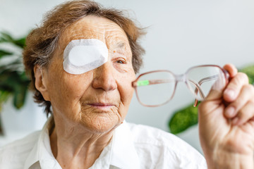 Elderly use eye shield covering after cataract surgery. - obrazy, fototapety, plakaty