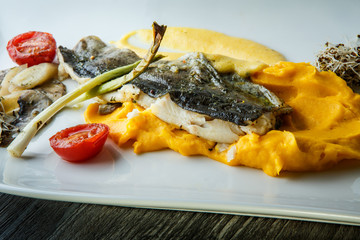 closeup puree exclusive decorated with grilled fish and vegetables