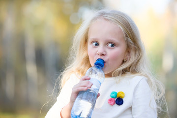 Positive girl child blonde gpit from a bottle of water