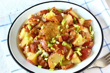 German potato salad with fried bacon and mustard dressing. traditional for oktoberfest festival.