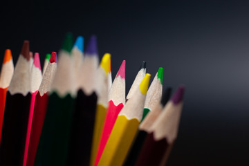 Sharpened pencils of different colors made of light wood isolated on black background.