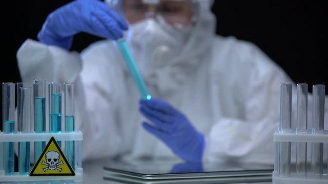 Lab worker inspecting test tubes with poison for sediments, dissolution process