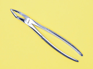 Dental surgical instrument on yellow background with copy space. Dental care concept