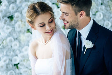 attractive bride and handsome bridegroom smiling and looking at each other