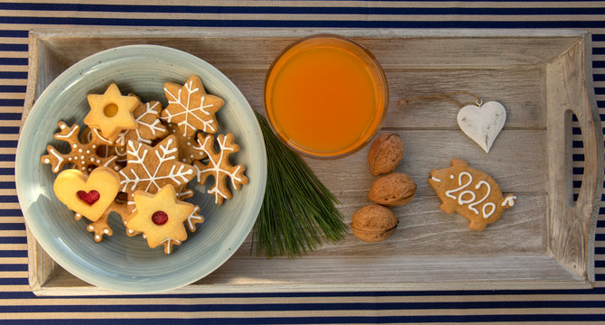 Christmas breakfast on wooden tray, fresh orange juice gingergread, shortcrust pastry cookies and pour feliciter pig 2020