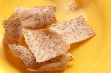 Yam chips, baked, olive oil, herbs and salt. Close view. Light yellow background. Vegan.