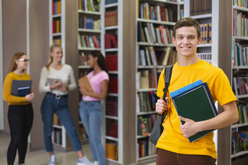 Excited guy posing next to bookshelves in library