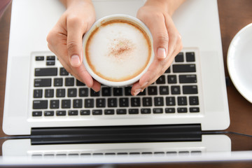 Woman hands holding a cup of coffee on laptop keyboard background. Labor day, Labour day concept. Relax time concept. Coffee time.