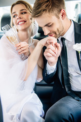 handsome bridegroom in suit kissing hand of his attractive bride