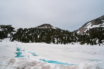 Frozen Emerald Lake in Lassen National Park with blue ice and snow, in California