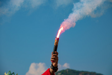 fan fire in hand against blue sky. the concept of victory, greeting, respect.