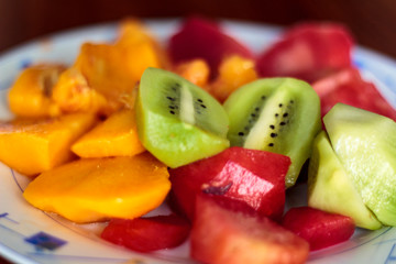 Plate with peeled fruit, plum, peach and kiwi