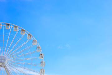 Fototapeta premium Ferris wheel in an amusement park at the summer. Copy space for text. Blue sky