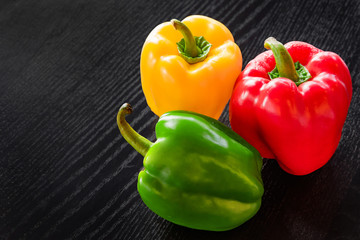 Freshly colored bell pepper in many colors Assemble the green, yellow, and red in a beautiful, bright, photographed position on a black wooden floor