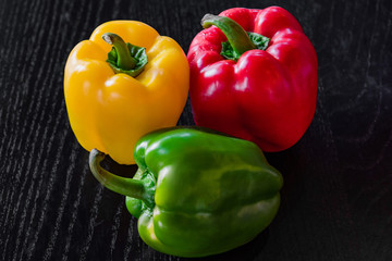 Freshly colored bell pepper in many colors Assemble the green, yellow, and red in a beautiful, bright, photographed position on a black wooden floor