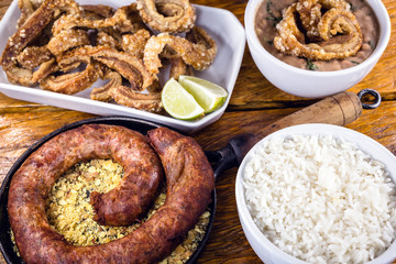 Typical food table in the interior of Brazil. Pork, beans, bean tutu, pork rinds, rice and farofa. Gastronomic tursimo concept, photo for restaurant menu.