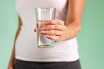 A pregnant girl holds a glass of water in her hand. Maintaining the health of mother and baby.