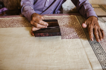 hands of a man doing dyeing pattern on cloth 