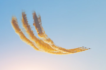 Plakat Aerobatic team group of fighters jet flies in the sky with brightly colored smoke under the setting sun in the evening sky