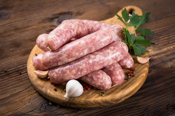 Raw sausages on the wooden board 