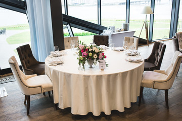 Beautiful composition with flowers on the tables and candles for guests at a wedding or a birthday party