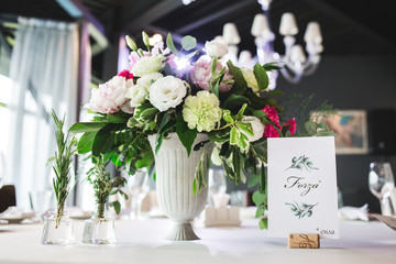 Beautiful composition with flowers on the tables and candles for guests at a wedding or a birthday party