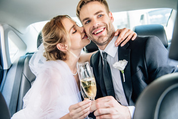 attractive bride and handsome bridegroom kissing and clinking with champagne glasses