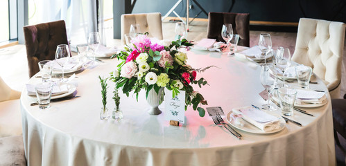 Beautiful composition with flowers on the tables and candles for guests at a wedding or a birthday party