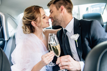 attractive bride and handsome bridegroom kissing and clinking with champagne glasses