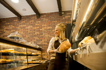 Pretty young woman selling fresh bread in the bakery