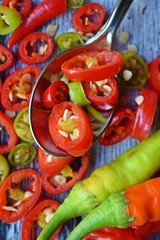 Close-up of sliced chili peppers on an old wooden surface, selective focus.