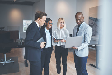 Businesspeople standing together in an office working on a lapto