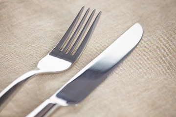 Table knife and fork on beige napkin.