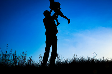 happy parent with child in the park outdoors silhouette