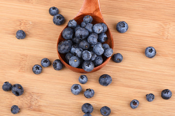 Top view. Blueberry berries in a wooden spoon on a wooden background.