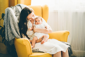 Young mother holding her newborn child. Mom nursing baby. Woman and new born girl relax in a...