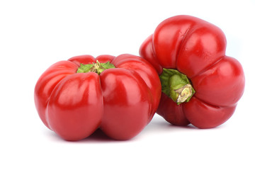 Two fresh red sweet peppers over white background.