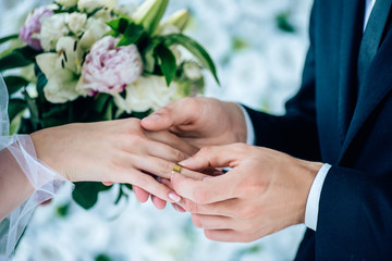 Obraz na płótnie Canvas cropped view of bridegroom putting wedding ring on finger