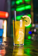 Orange cocktail in a tall glass and a slice of lemon.