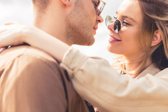 attractive woman hugging and kissing with handsome man in sunglasses