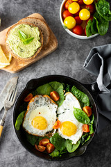 Fried sunny eggs with spinach, avocado toast and fresh tomatoes. healthy breakfast food.