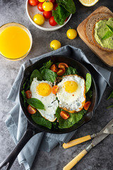 Fried sunny eggs with spinach, avocado toast and fresh tomatoes. healthy breakfast food.