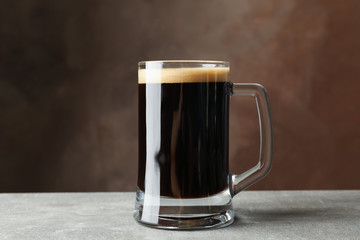 Glass of dark beer on grey table, space for text