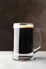 Glass of dark beer on grey table, space for text