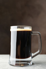 Glass of dark beer on grey table, space for text